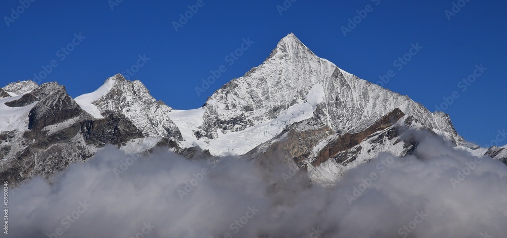 Peak of mount Weisshorn reaching out of clouds