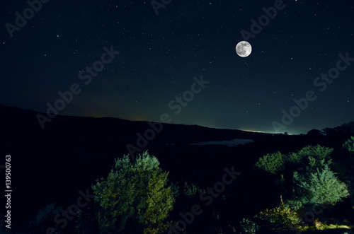 Beautiful night landscape of big full moon rising over the mountain road with hill and trees. Forest and mountains of south part of Azerbaijan. Masalli Yardimli