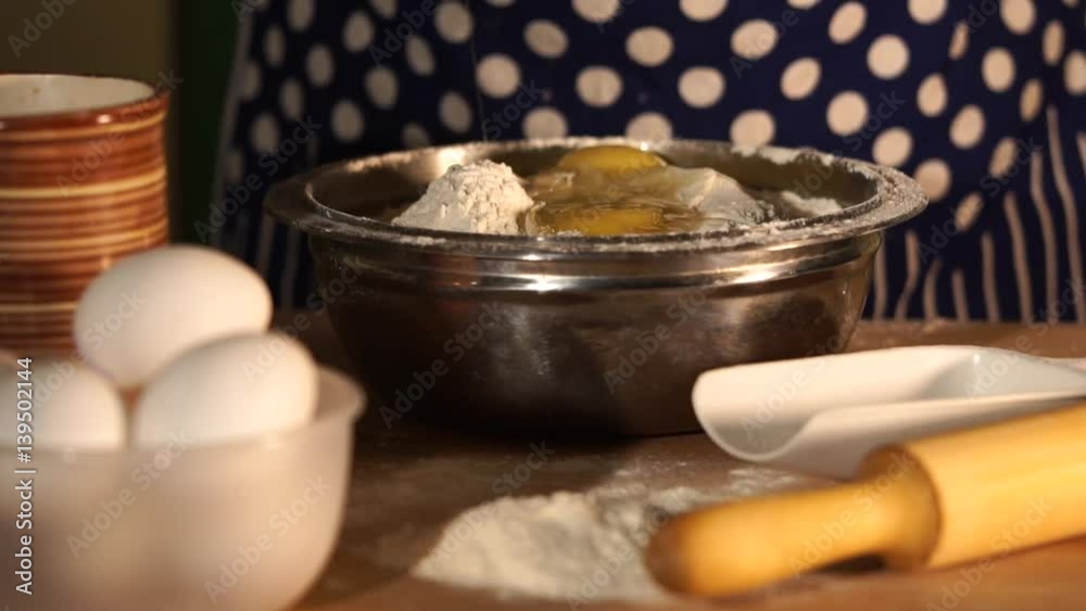 Slow motion shot of a raw egg falls into the bowl with the flour, which stands on the table. The baker puts on the plate whites and yolks to make the dough for pies or cookies. Slow motion shot of a raw egg falls into the bowl with the flour, which stands on the table. The baker puts on the plate whites and yolks to make the dough for pies or cookies.