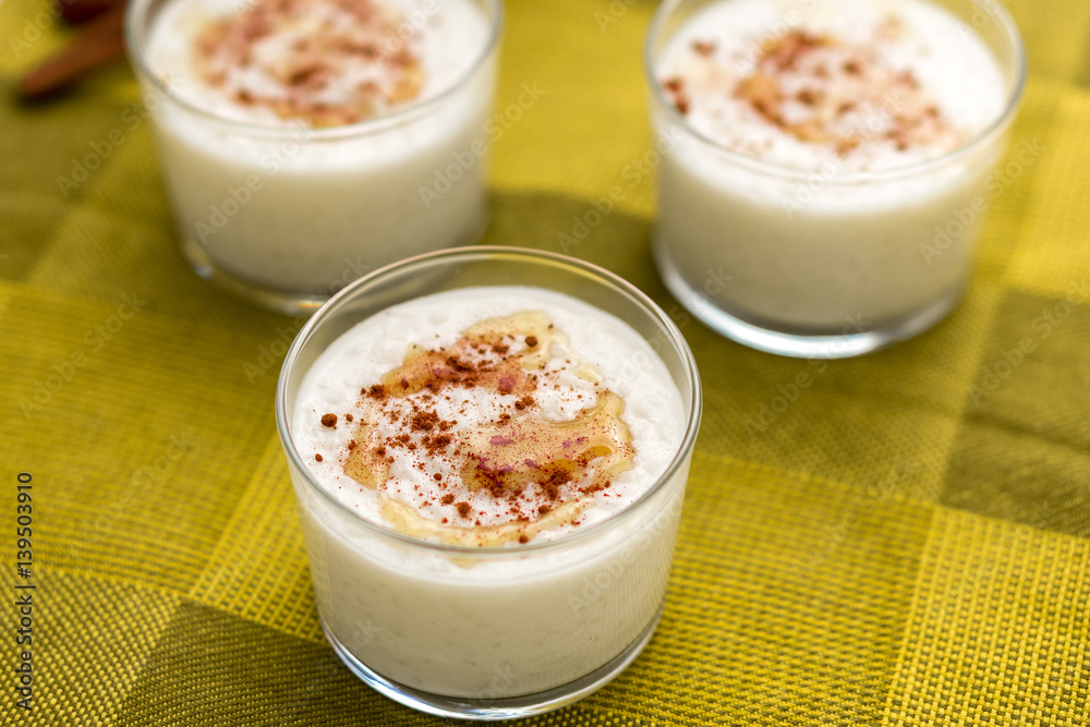 Coconut rice pudding with maple syrup & Cinnamon. Coconut flavored rice pudding dessert with maple syrup drizzle on top and sprinkled cinnamon served in glass bowl. Coconut rice pudding with maple syrup & Cinnamon. Coconut flavored rice pudding dessert with maple syrup drizzle on top and sprinkled cinnamon served in glass bowl.