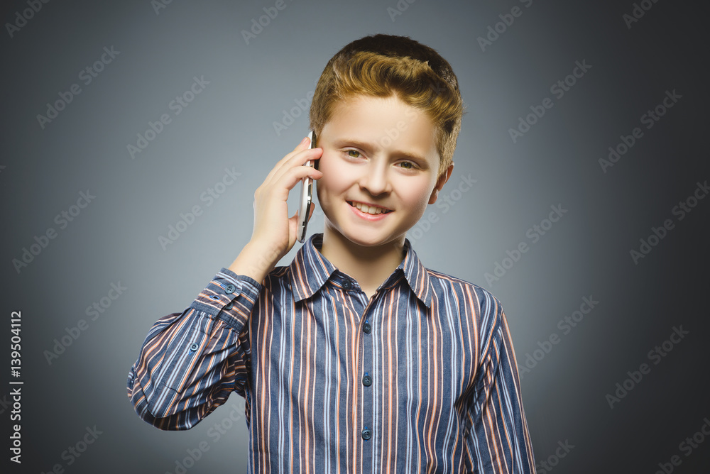 Closeup Portrait of happy boy with mobile or cell phone on gray background Closeup Portrait of happy boy with mobile or cell phone on gray background