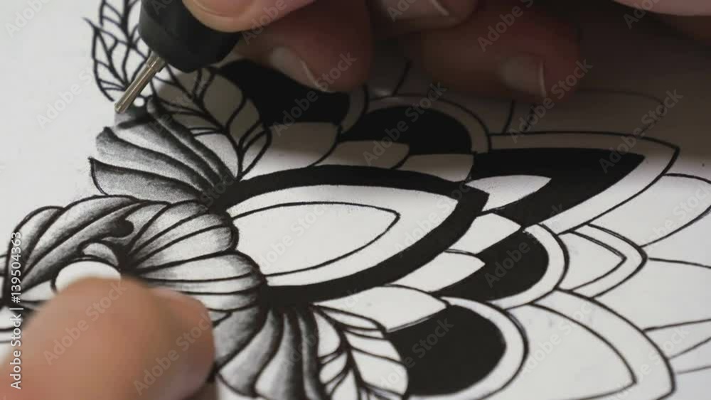 Tattoo master drawing sketch of black pen close-up Tattoo master drawing sketch of black pen close-up