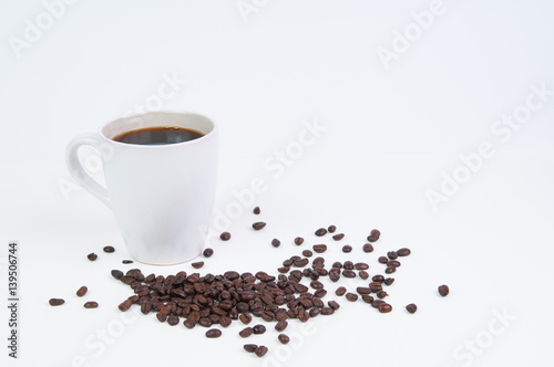 Cup of black coffee in a white mug with coffee beans