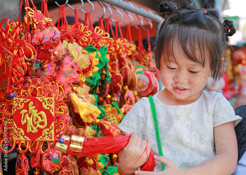 Little girl in Chinese dress against traditional chinese red decorations are very popular during the Chinese new year Festival at chinatown in bangkok, Thailand.