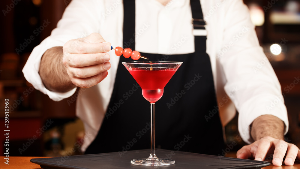 Barman in making cocktail at a nightclub. Nightlife concept. No face. Decorating drink