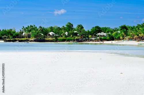 Beautiful white coral sand beach with palms and cottages, turquoise blue ocean