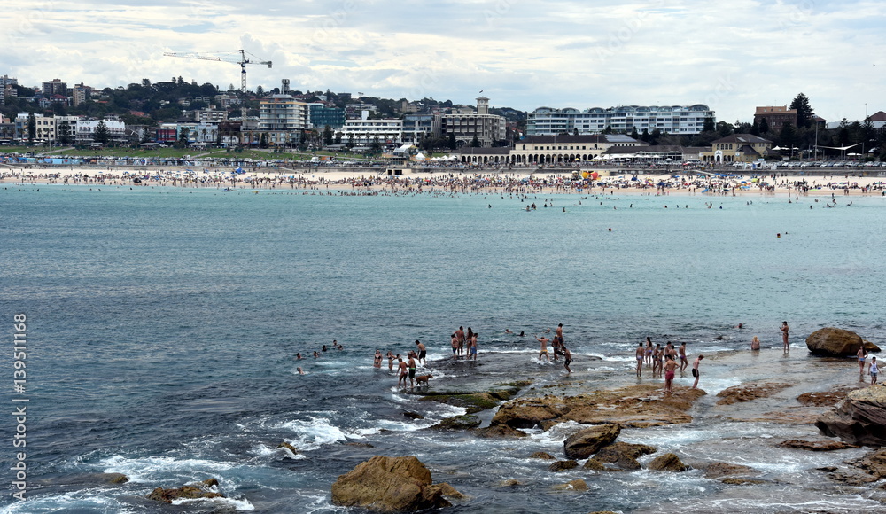Sydney, Australia - Feb 5, 2017. People relaxing, swimming and sun bathing on Bondi beach. Bondi beach is one of the most famous tourist sites in Australia. Sydney, Australia - Feb 5, 2017. People relaxing, swimming and sun bathing on Bondi beach. Bondi beach is one of the most famous tourist sites in Australia.