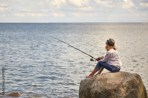 woman fisher sitting on summer sea beach