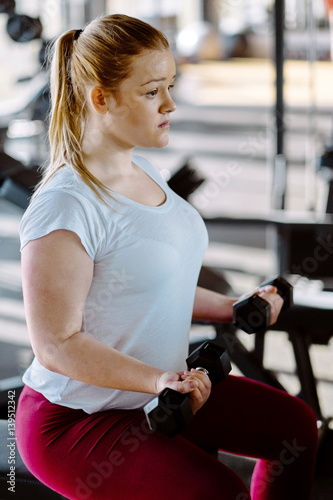 Beginner girl exercising in fitness gym with dumbells