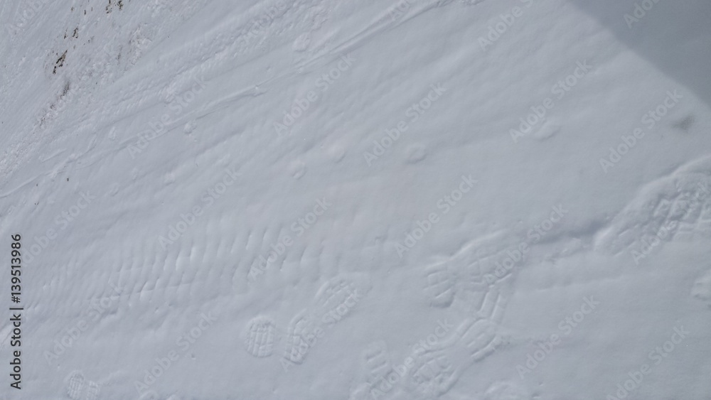 Fototapeta premium Tire tread and boot tracks on a snow packed road