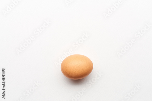 Single simple brown egg on white background
