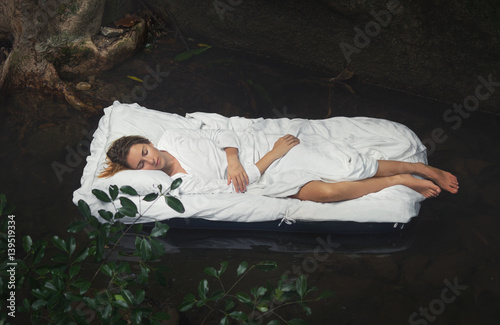 A hidden place. Sleeping woman in deep forest lies on airbed