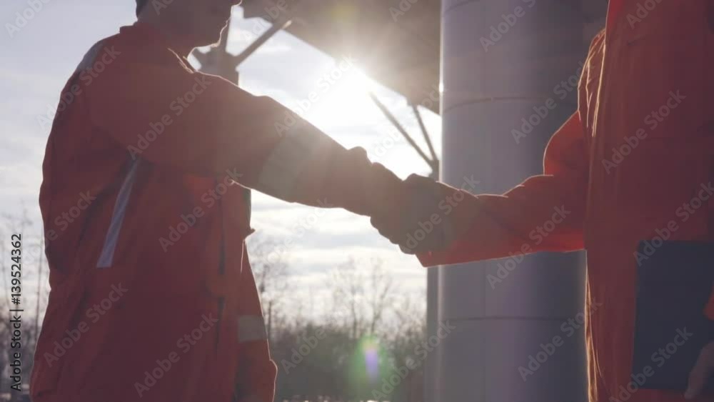 Closeup view of two construction workers in orange uniform and hardhats ...