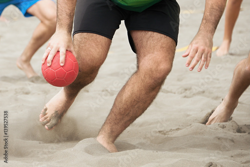 Beach handball players in action on a sunny day