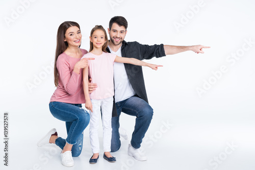 Happy young family with one child pointing away with fingers