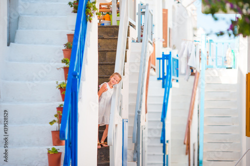 Beautiful girl at street of typical greek traditional village with amazing steps and white walls on Mykonos