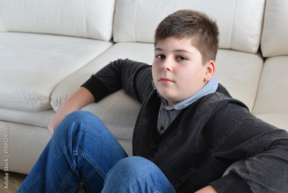 13 year boy sitting near the sofa in room
