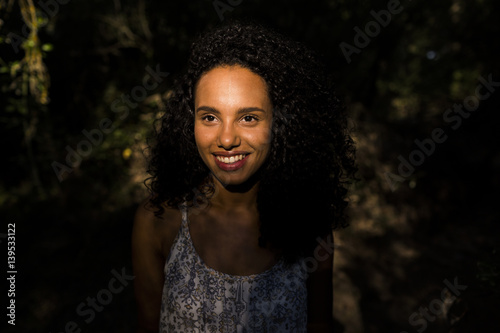 portrait outdoors of a beautiful young afro american woman smiling at sunset. Black background. Lifestyle
