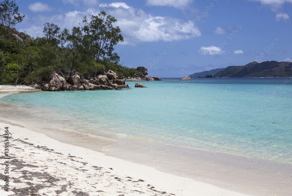 Picturesque beach with white sand decorated with granitic boulders  on the background turquoise ocean on Seychelles