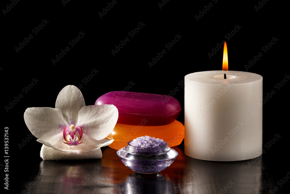 White orchid flower, candle, soap and sea salt for spa procedures on black background White orchid flower, candle, soap and sea salt for spa procedures on black background