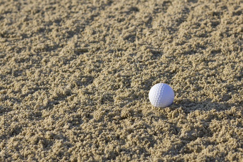 Lonely golf ball in sand bunker.