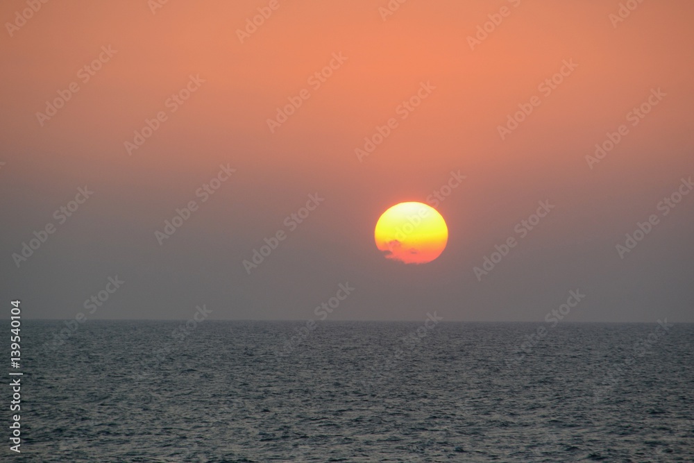 Circular yellow and orange sun setting over the ocean off of Cartagena