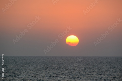 Fototapeta Naklejka Na Ścianę i Meble -  Circular yellow and orange sun setting over the ocean off of Cartagena