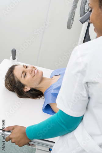 Radiologist Preparing Female Patient For X-ray In Hospital