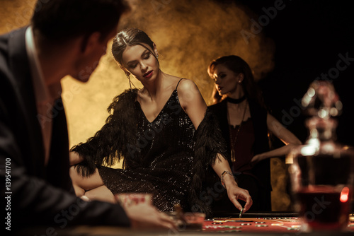 Tela Man looking at beautiful woman sitting on poker table in casino