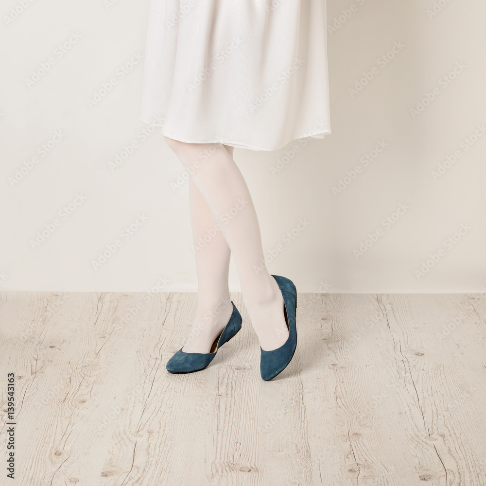 Female legs in white tights, skirt and ballet flats on a white background. Female legs in white tights, skirt and ballet flats on a white background.