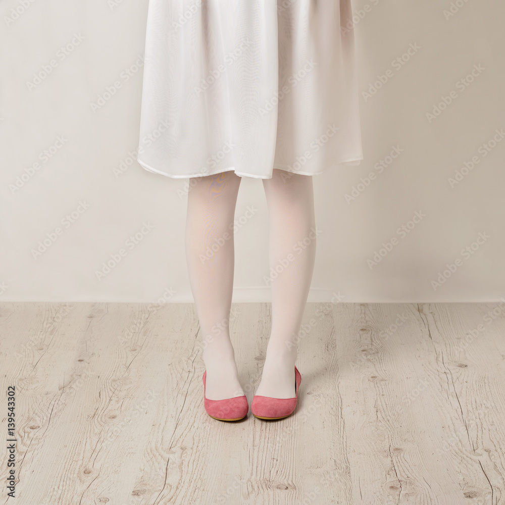 Female legs in white tights, skirt and ballet flats on a white background. Female legs in white tights, skirt and ballet flats on a white background.