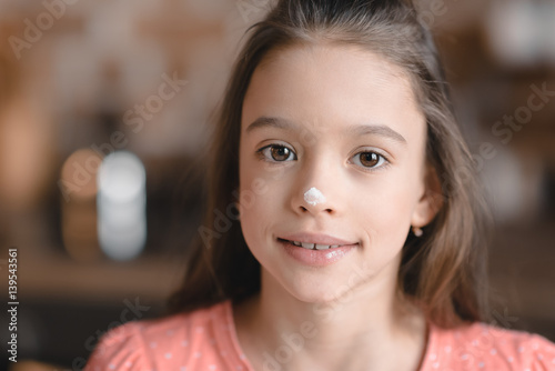 'Cute little girl with flour on nose smiling at camera