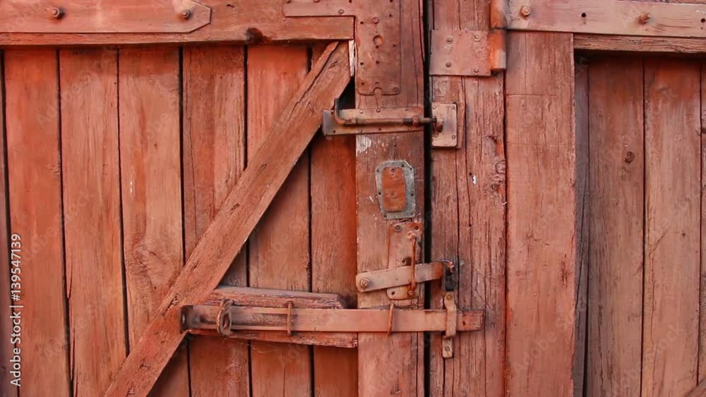 Old rural wooden closed gate door horizontal panning. Old cracked planks, rusty iron door mechanisms. Focus on full depth. Old rural wooden closed gate door horizontal panning. Old cracked planks, rusty iron door mechanisms. Focus on full depth.