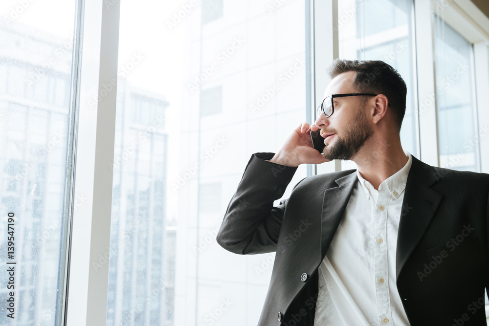 Bearded business man talking on phone and looking away Bearded business man talking on phone and looking away