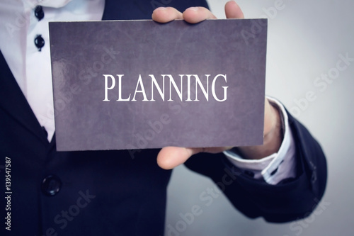 Planning - Businessman holding chalkboard with text.