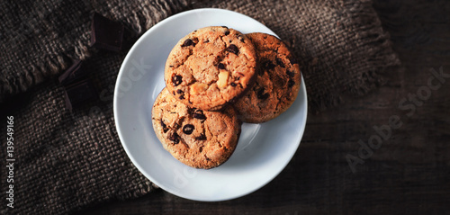 Chocolate chip cookies on white plate dark old wooden table with place for text.,  freshly baked. Selective Focus with Copy space..