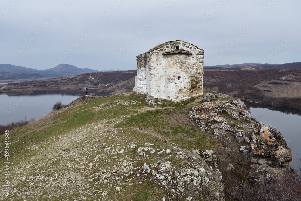 The small Orthodox church of Saint Ivan Letni from year 1350 perched on top of rocky hill above Pchelina Lake, Radomir region, Bulgaria