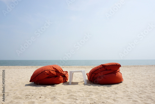 Orange beach bed with white plastic table on the beach