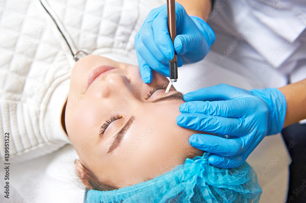 Permanent make-up wizard makes eyebrow correction procedure. Permanent make-up wizard makes eyebrow correction procedure.