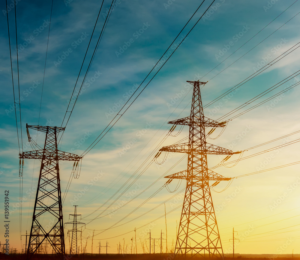 High-voltage power transmission towers in sky background.