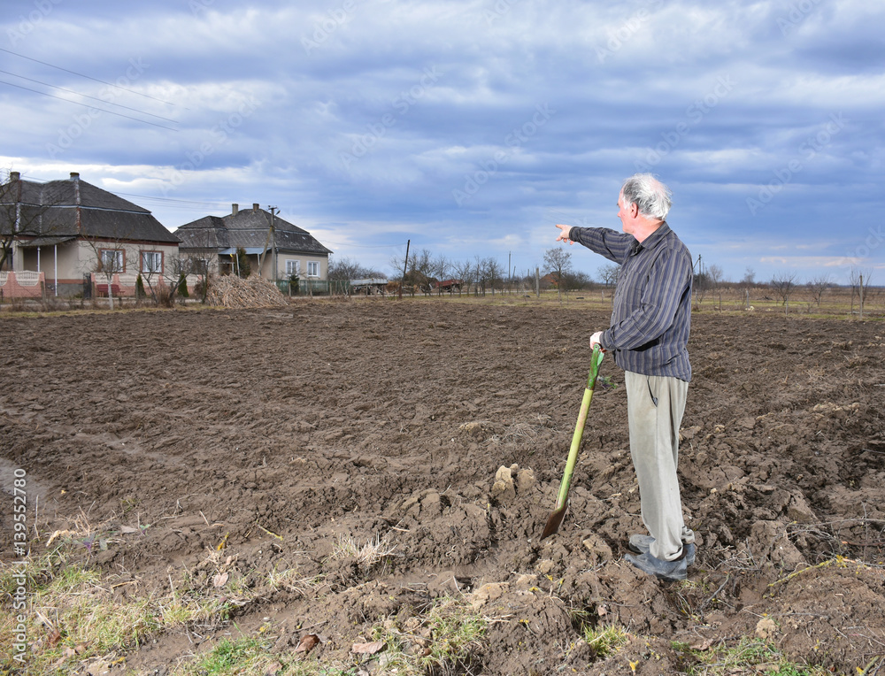 Farmer standing with a shovel on the field Farmer standing with a shovel on the field