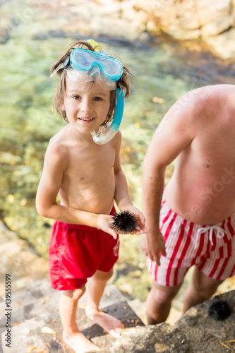 Cute child, holding sea urchin on the beach photo