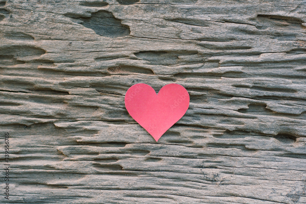 Red blank paper note with heart shape on grunge wooden background