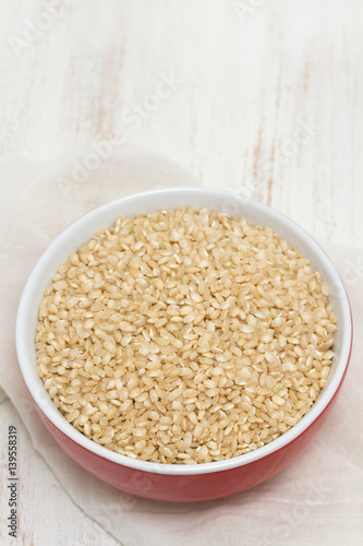 raw rice in red bowl on wooden background © Natalia Mylova