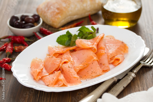 smoked salmon on white plate on wooden background