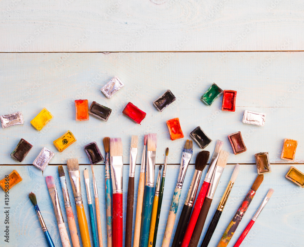 Naklejka premium Paints, brushes on the white wood background. The workplace of the artist. Banner for school