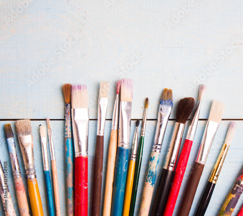Brushes on the blue wood background. The workplace of the artist. Banner for school