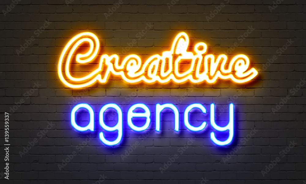 Creative agency neon sign on brick wall background.
