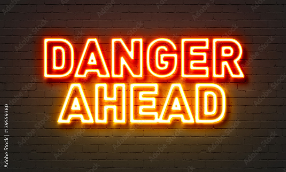 Danger ahead neon sign on brick wall background. Danger ahead neon sign on brick wall background.