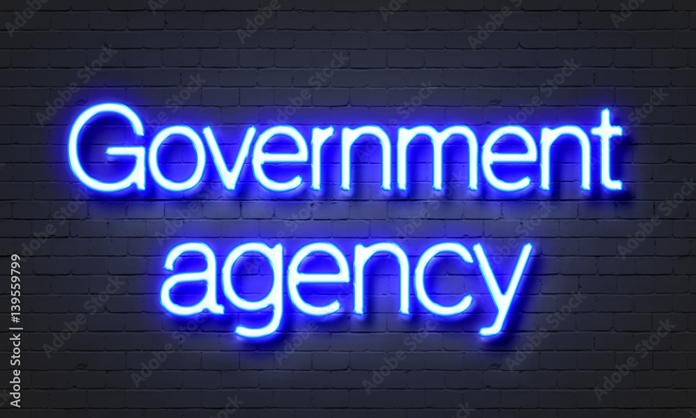 Government agency neon sign on brick wall background.